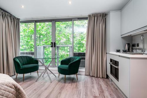 a bedroom with a table and two green chairs at The Regent in Cambridge