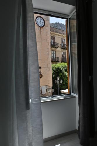 a window with a clock on a brick building at Suite Garibaldi in Cefalù