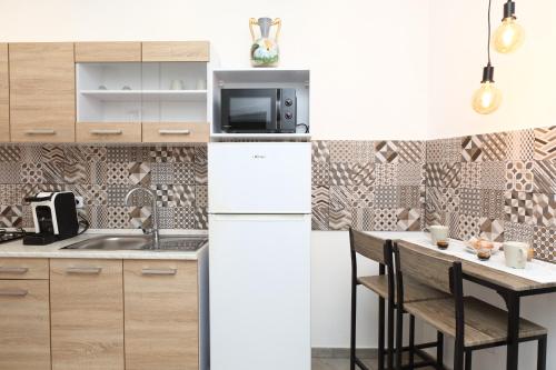 a kitchen with a white refrigerator and a table with chairs at Suite Garibaldi in Cefalù
