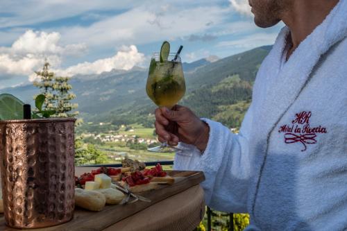 a man holding a drink with a plate of food at La Roccia Wellness Hotel in Cavalese