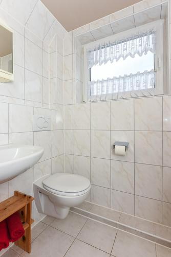 a white bathroom with a toilet and a sink at Pension Hohaus in Neuharlingersiel