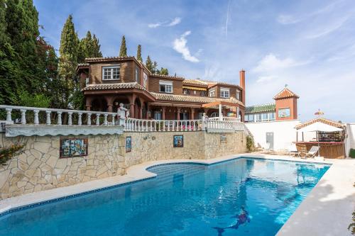 una villa con piscina di fronte a una casa di Villa Geneviève Costa del Sol a Mijas Costa