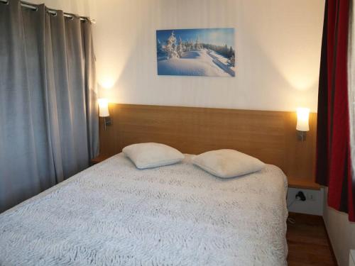 une chambre avec un lit avec deux oreillers dessus dans l'établissement Charmant 2P pour 6 pers avec piscine, jacuzzi et balcon sud-ouest - Les Orres 1800 - FR-1-322-423, aux Orres