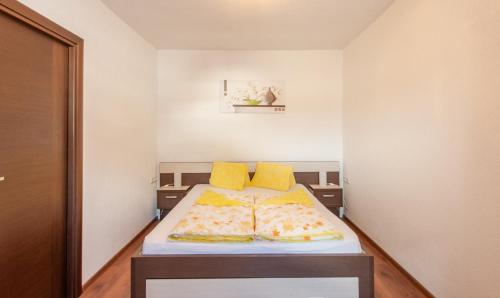 Una cama en una habitación con almohadas amarillas. en Appartement 101, en Bichlbach