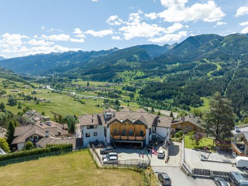 an aerial view of a house with mountains in the background at La Roccia Wellness Hotel in Cavalese