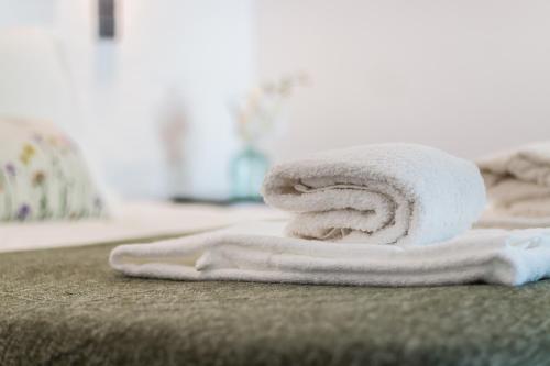 een stapel handdoeken bovenop een bed bij Casas Barulho - Villa Jacaranda A8 in Albufeira