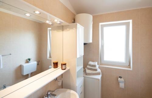 a bathroom with a toilet and a sink and a window at Sisi Apartment in Vabriga