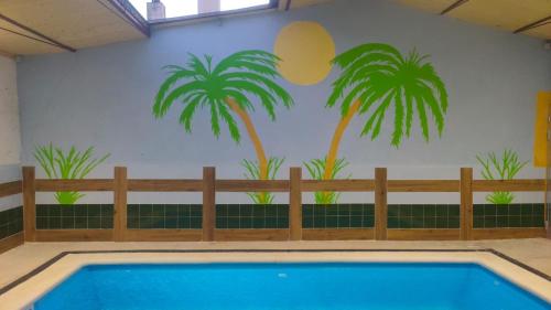 un murale di palme su un muro accanto alla piscina di Casa Rural Baños de la Reina con piscina climatizada a Vega de Santa María