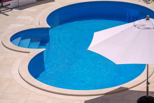 a white umbrella sitting next to a blue swimming pool at Hektorovic poolside apartments in Bol
