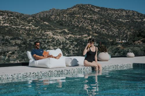 a man and woman sitting on a couch next to a swimming pool at Pignolia Suites - Adults Only in Ierápetra