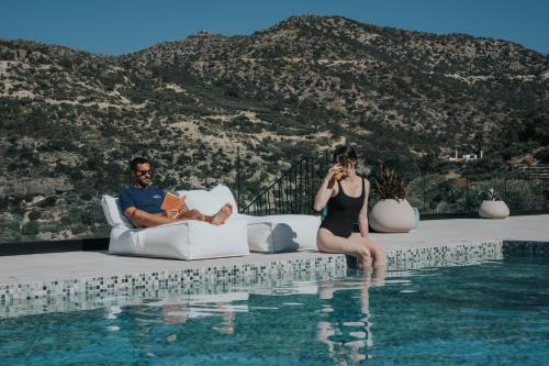 a man and woman sitting on a couch next to a swimming pool at Pignolia Suites - Adults Only in Ierapetra