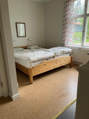 a bedroom with a wooden bed in a room with a window at Trunna Vandrarhem & Konferens in Orsa