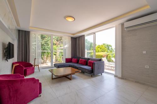 a living room with a couch and two red chairs at Ada Villas in Kusadası