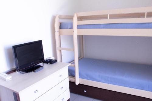 1 dormitorio con literas, TV y escritorio en Le Marais - Village Vacances, en Meschers-sur-Gironde
