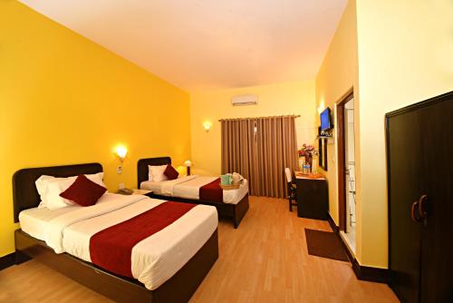 two beds in a hotel room with yellow walls at Sacred Boutique Hotel in Kathmandu