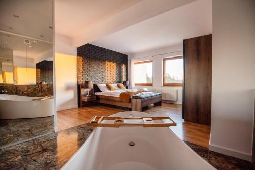 a bathroom with a tub and a bed in a room at Rezydencja Margonin in Margonin