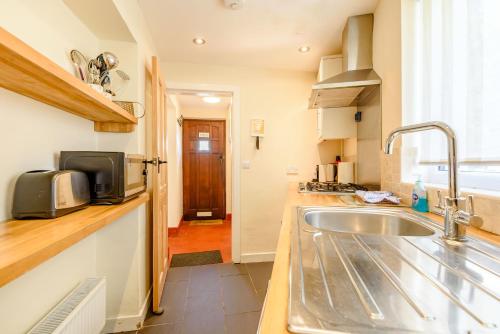 a kitchen with a sink and a microwave at Kynaston Cottage in Aberdyfi