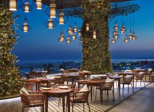 een restaurant met tafels, stoelen en verlichting bij Amanti, MadeForTwo Hotels - Ayia Napa in Ayia Napa