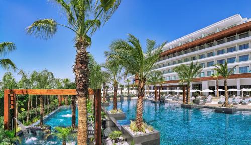 un complejo con una piscina con palmeras y un edificio en Amanti, MadeForTwo Hotels - Ayia Napa en Ayia Napa