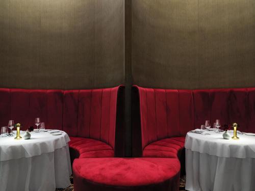 a dining room with two tables and red chairs at Amanti, MadeForTwo Hotels - Ayia Napa in Ayia Napa