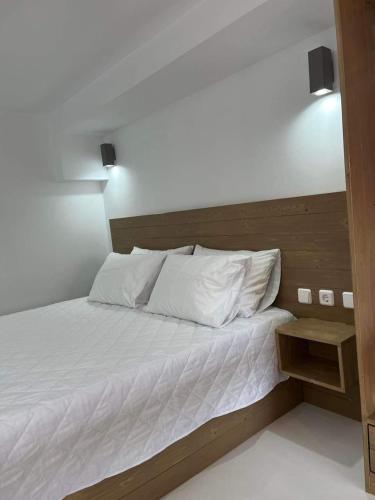sypialnia z białym łóżkiem z drewnianym zagłówkiem w obiekcie OASIS rooms w mieście Karistos