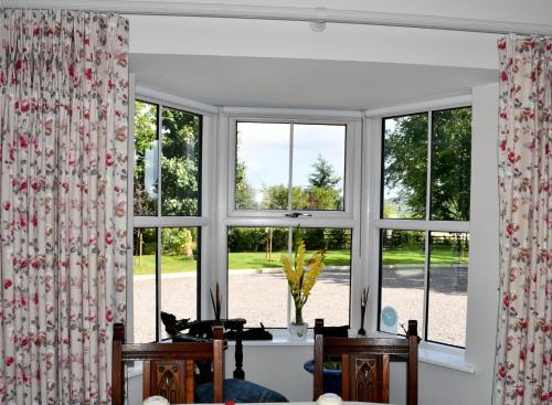 ein Wohnzimmer mit Fenstern sowie einem Tisch und Stühlen in der Unterkunft Kilbawn Country House in Kilkenny