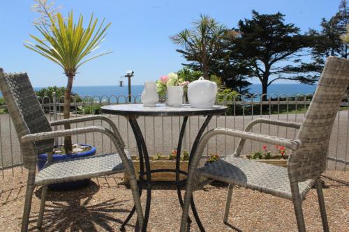 a table and two chairs with a table and two vases at Sandcastles - Mount Brioni in Downderry