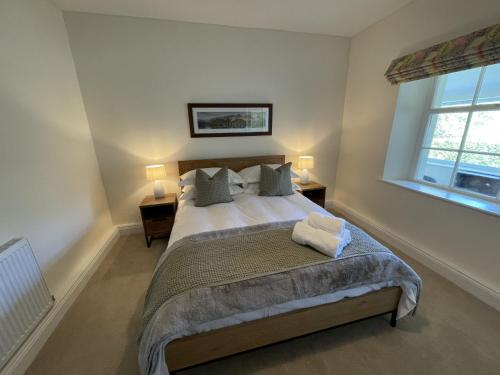 sypialnia z łóżkiem z 2 lampami i 2 oknami w obiekcie Brandlehow w mieście Portinscale