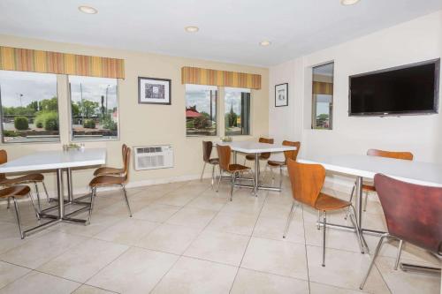 a dining room table with chairs and a television at Super 8 by Wyndham Montrose in Montrose