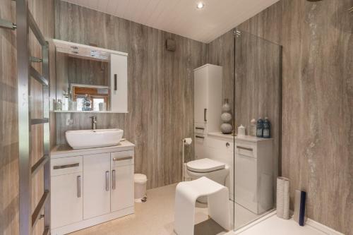 a bathroom with a white sink and a toilet at Violet Lodge - Norfolk Holiday Properties in Neatishead