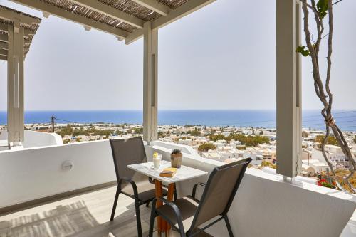 a table and chairs on a balcony with a view of the ocean at Acropole Sunrise in Kamari