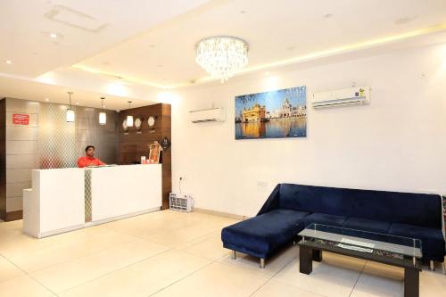 a man standing at a counter in a room with a blue couch at Hotel Winner Inn in Amritsar