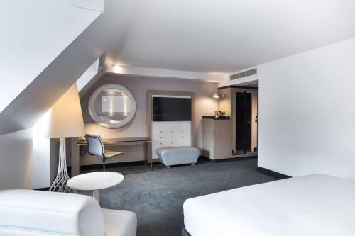 a white room with a white bed and a white chair at Radisson Blu Hotel, Edinburgh City Centre in Edinburgh