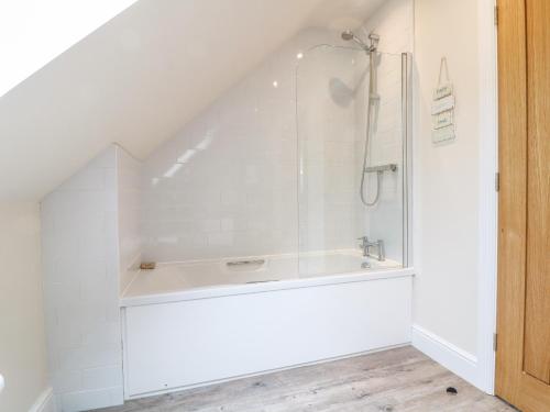 biała łazienka z prysznicem na poddaszu w obiekcie Tawny Cottage w mieście Burford