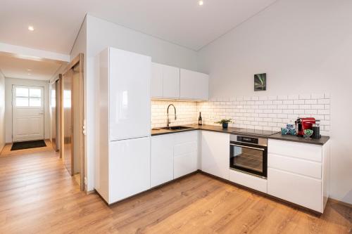 a kitchen with white cabinets and a wooden floor at Lundur Apartments in Reykjavík