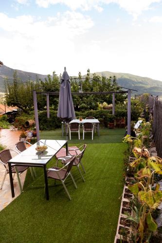 a patio with tables and an umbrella and grass at El Rencuentro in Villarejo del Valle