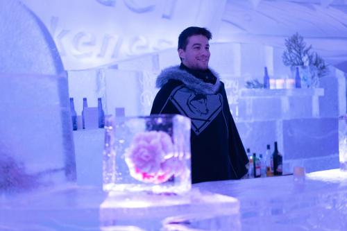 a man standing behind a table with a vase with a flower in it at Snowhotel Kirkenes in Kirkenes