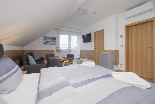 a bedroom with a large bed and a living room at Willa Szamotulanka - Pokoje Wakacyjne Rewal - Plac Zabaw & Grill - by Noclegi Renters in Rewal