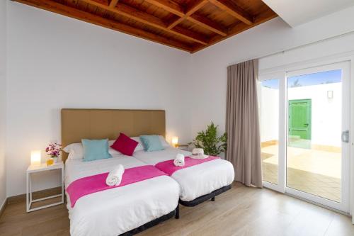 a bedroom with two beds and a sliding glass door at Villa Arena by Villa Plus in Playa Blanca