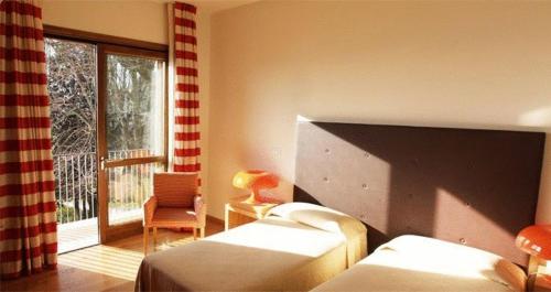 a bedroom with two beds and a window and a chair at Le Querce Hotel in Salsomaggiore Terme