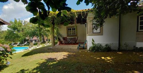 a house with a yard with chairs and a pool at Casa da Roseira in Ponte de Lima