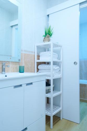 a bathroom with a sink and a white shelf at Pretty town hall apartment in Tarragona
