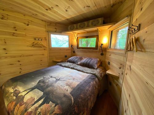 a bedroom with a bed in a log cabin at Les Cabanes De Pyrene in Cazarilh