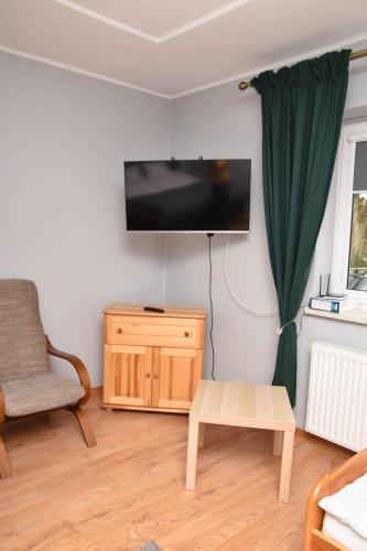 a living room with a tv and a chair and a table at Gospodarstwo Agroturystyczne z BASENEM & SPA i Alpakami in Ełk