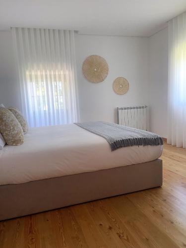 a bedroom with a bed with white walls and wooden floors at Casa do Afonso in Brufe