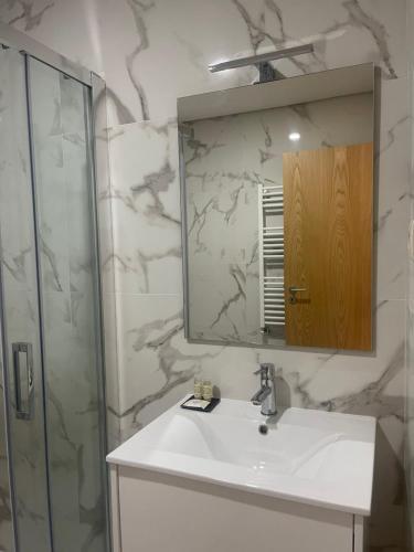 a bathroom with a sink and a mirror and a shower at Casa do Afonso in Brufe