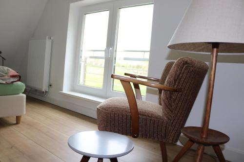 a living room with a chair and a lamp and a table at Kleines Haus am Feld in Rehna