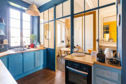 une cuisine avec des armoires bleues et une table dans l'établissement Le Ara Bleu - Bel appartement de caractère, à Saint-Malo