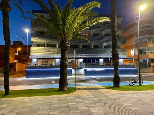 un edificio de noche con palmeras delante en Hotel Neptuno, en San Pedro del Pinatar
