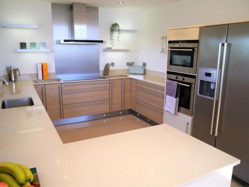 a kitchen with wooden cabinets and stainless steel appliances at Annapurna in Portpatrick